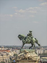 Statue of a horseman on a pedestal, surrounded by city view and blue sky, budapest, danube, hungary