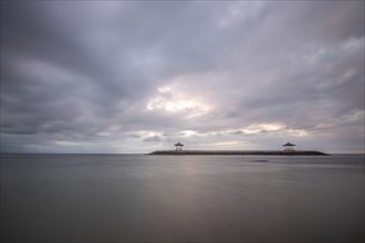 Beautiful seascape in the morning. Tropical sandy beach with breakwater and reflection of the sky
