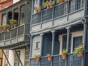 Multi-storey buildings with wooden balustrades and flower pots in front of the windows, la palma,