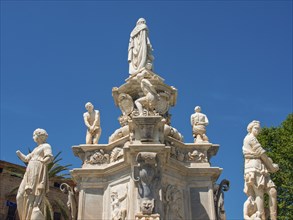 Detailed view of a historic fountain with several statues under a clear blue sky, palermo, sicily,