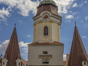 A historic clock tower and church towers against a blue sky with few clouds, Dürnstein, Wachau,