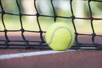 Tennis scene with black net, ball on white line in low angle view