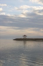 Beautiful seascape in the morning. Tropical sandy beach with breakwater and reflection of the sky