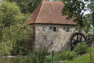 Historic mill building with a wooden wheel and river, surrounded by green nature, Eibergen,