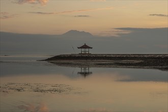 Beautiful seascape in the morning. Tropical sandy beach with breakwater and reflection of the sky