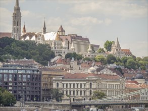 Historic buildings on a hill with red roofs and gothic architecture under a cloudy sky, budapest,