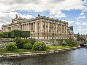 Impressive building by a river under a partly cloudy sky, surrounded by cityscape, stockholm,