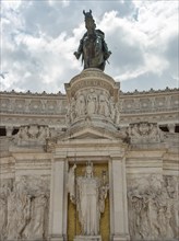 Detailed view of a monument in Rome with equestrian statue and sculptures on it under a cloudy sky,