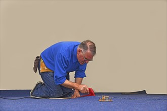 A floorlayer uses a hot iron to seal the glue strip in a join a new carpet