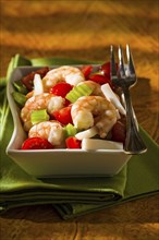 Shrimp salad with squid tomatoes celery inside a white bowl