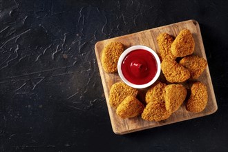 Chicken nuggets with bbq sauce on a black background, shot from above with a place for text. Crispy