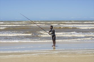 Young man fishing on beach, sport fishing