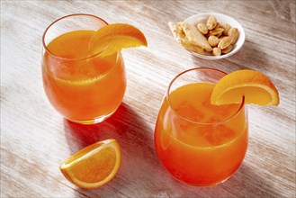 Orange drinks and a salty snack on a wooden background, fresh pressed juice with fruit slices on a