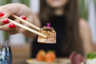 Woman eating delicious gunkan sushi, closeup on chopsticks