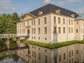 Majestic castle with white facades and blue roofs, perfectly reflected in the surrounding moat,