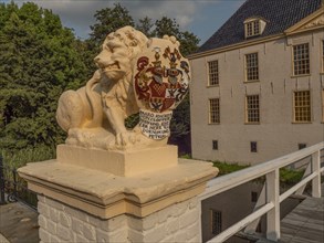 Lion statue with coat of arms on a bridge in front of a historic building, dornum, east frisia,