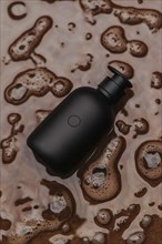 A black bottle surrounded by brown soap bubbles and foam, AI generated