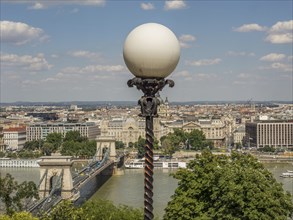 Street lamp with ball lamp and view of the cityscape and the river under a blue sky, budapest,