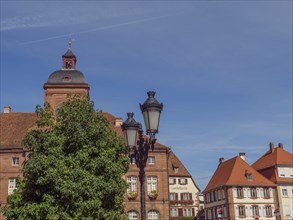 Historic buildings with red tiled roofs next to lanterns and trees under a clear sky, Weissenburg,