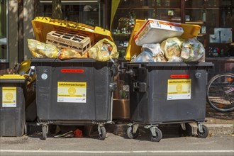 Overfilled waste containers for lightweight packaging standing on the street, Germany, Europe