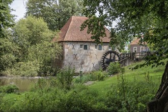 Mill with wooden wheel by the river, surrounded by lush vegetation and trees, Eibergen, Gelderland,