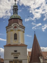 A towering clock tower and a steep church spire against a cloudy sky, Dürnstein, Wachau, Danube,