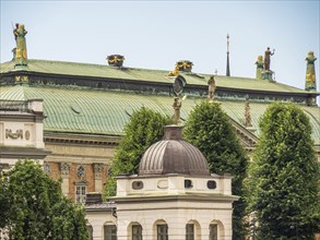 Historic buildings with green roofs and statues, surrounded by trees under a clear sky, stockholm,