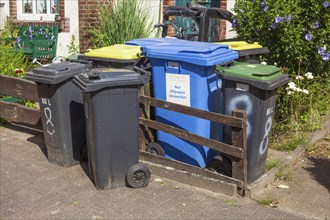 Colourful different dustbins standing in front of a house entrance, Delmenhorst, Lower Saxony,