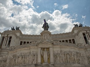 A grandiose monument with an equestrian statue and impressive sculptures under a cloudy sky, Rome,