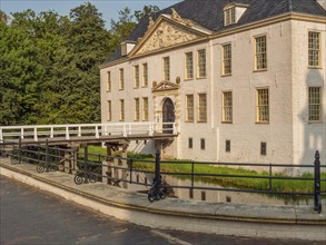 Historic white castle on the moat with decorative façade and blue roof, connected by a bridge,