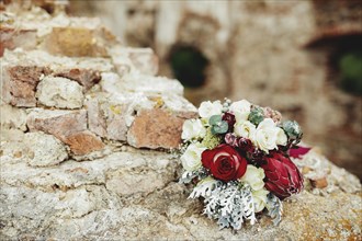 Wedding bouquet on the broken brick fence. Blurred background.