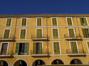 Yellow, spacious building with green shutters and balconies, a typical urban background, palma de