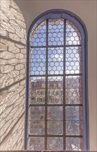 Old stained glass window of a church with shadows and blue sky