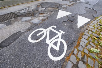 A cycle path pictogram on a road with potholes in Mönchengladbach, Germany, Europe