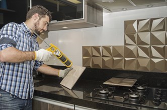 Man renovating, renovating the kitchen, installing tile on the wall