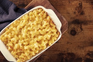 Macaroni and cheese pasta in a casserole, shot from the top on a rustic background with copy space,