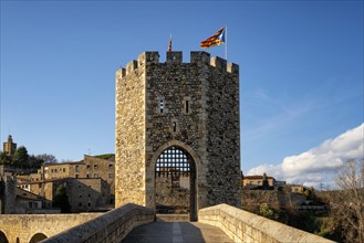 Besalu historic medieval city with Catalonia flags on the stone bridge tower crossing El Fluvia