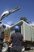 GREYMOUTH, NEW ZEALAND, OCTOBER 21, 2020: A crane operator works on lifting a small building from a