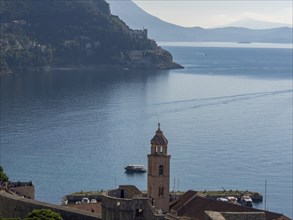 Historic bell tower with a picturesque coastal landscape and mountains in the background,