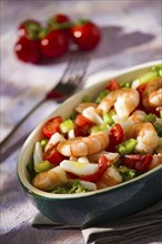 Salad of shrimps inside an oval bowl over a grey napkin