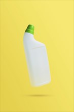 Levitating or flying blank toilet cleaner bottle with green cap. Isolated on yellow background.