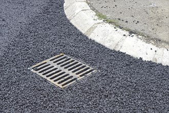 Storm drain and new asphalt at street corner