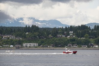 The Canadian Coast Guard sails off the east coast of Vancouver Island, past the village of Campbell