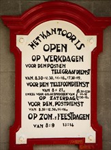 Enkhuizen, Netherlands, June 2022. Old announcement of the opening hours of Dutch post office from