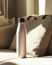 A silver metal water bottle with a black cap is illuminated by morning light, casting shadows on a