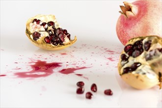 Half pomegranate and seeds on white background