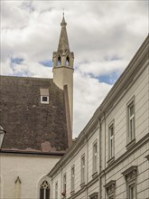 Historic building with a church in the background and a tower under a slightly cloudy sky,