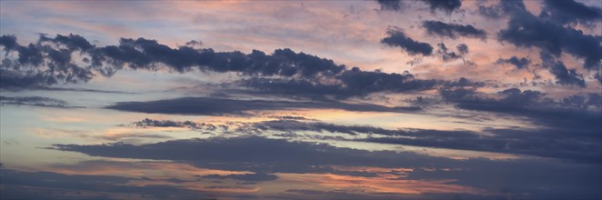 Panoramic view of the vast sky, dominated by a variety of clouds, hints of pink and blue suggest