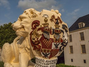 Detailed view of a lion statue with coat of arms, building in the background, dornum, east frisia,