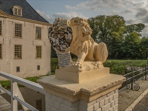 Lion statue with coat of arms on bridge wall, buildings and nature in the background, dornum, east